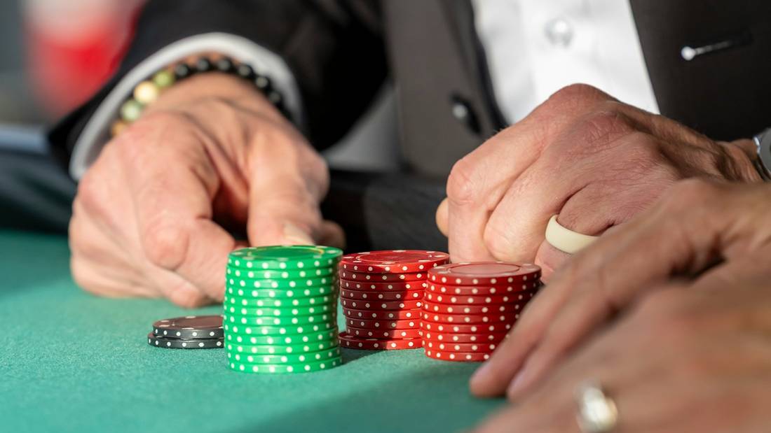 Tangan pemain meraih chip poker di atas meja