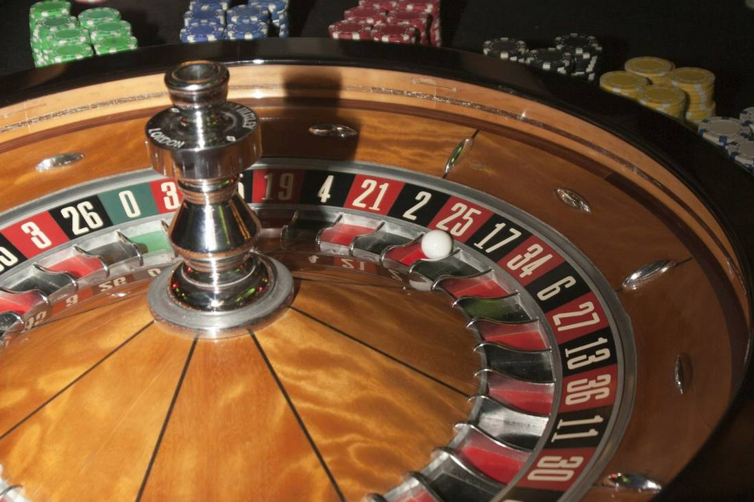 Meja roulette dengan roda kayu dan tumpukan chip warna-warni