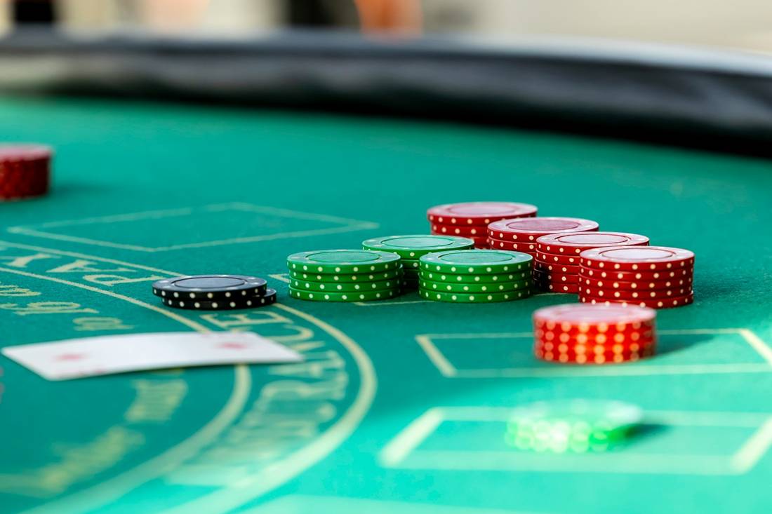 Chip poker merah dan hijau tersebar di atas meja felt hijau