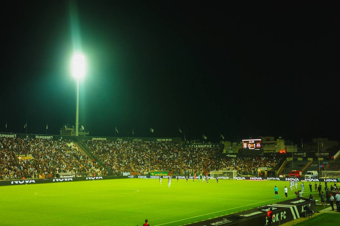 Pertandingan sepak bola malam hari di stadion dengan lampu sorot