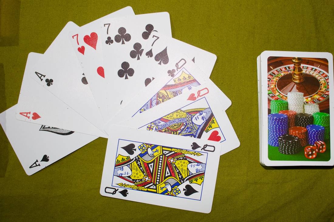 Kartu remi dan tumpukan chip di atas meja hijau